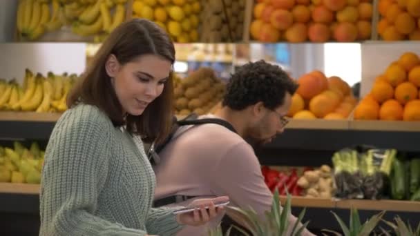 Nabywcy wielonarodowi korzystający z listy zakupów na rynku — Wideo stockowe