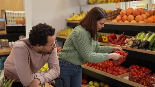 Грустный мужчина смотрит на женщину, выбирающую веганские продукты — стоковое видео