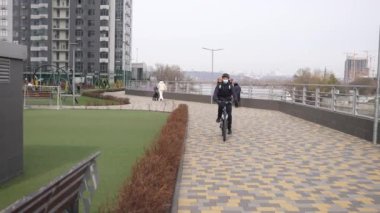 Park yolunda bisiklete binen maskeli teslimatçı.