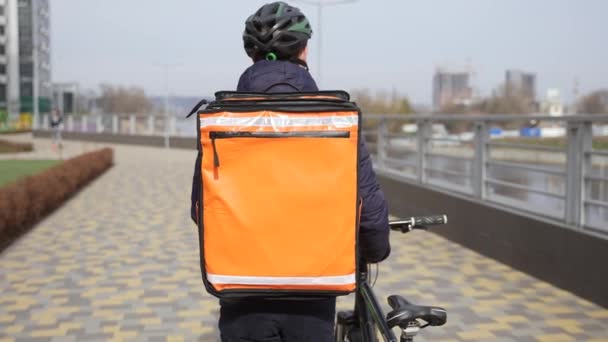 Correio de alimentos com mochila térmica transportando bicicleta — Vídeo de Stock