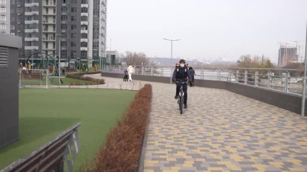 Cara de entrega mascarado andar de bicicleta no caminho do parque — Vídeo de Stock