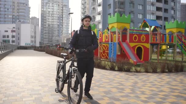 Entregador transportando bicicleta através do pátio da cidade — Vídeo de Stock