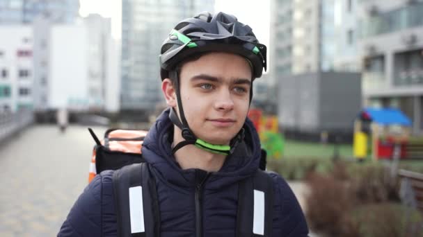 Jovem entregador de capacete andando rua abaixo — Vídeo de Stock