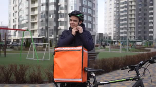 Repartidor cansado quitándose el casco de la bicicleta al aire libre — Vídeos de Stock