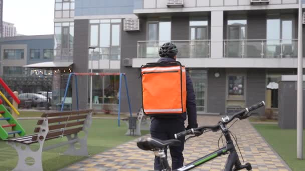 Correio com mochila térmica caminhando para a construção — Vídeo de Stock