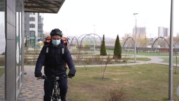 Маскований кур'єр їде на велосипеді до місця доставки — стокове відео