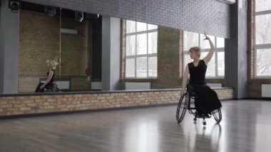 Balo salonunda tekerlekli sandalyede dönen engelli dansçı.