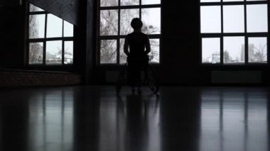 Pencereye yaslanmış engelli kadın dansçı silueti