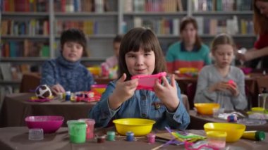 Genç otistik kız kameraya balçık geriyor.