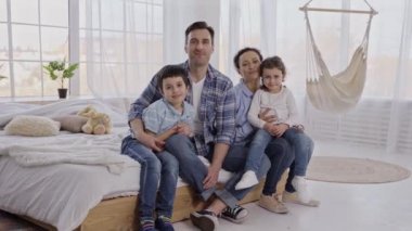 Çocuklar içeride kameralara poz verirken arkadaş canlısı bir aile.