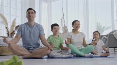 Evde yoga yapan çocuklu çekici bir aile.