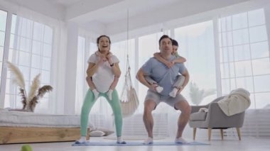 Sportif çift arkada çocukları olan çömelme hareketleri yapıyor.