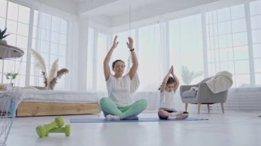 Evde annesiyle yoga yapan sevimli küçük bir kız.