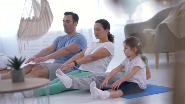 Позитивная семья с детьми, практикующими йогу — стоковое видео