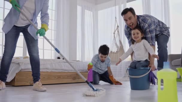 Радостный папа ездит дочь на ведре во время уборки — стоковое видео
