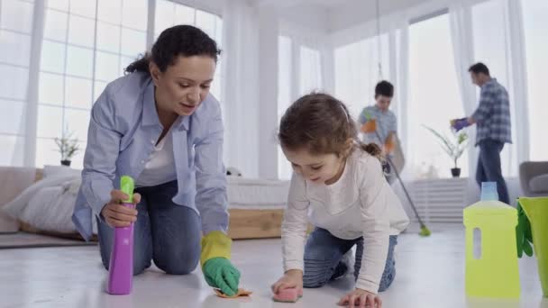 Мати з маленькою донькою витирає підлогу вдома — стокове відео