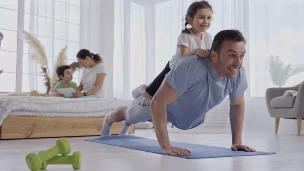 Ayah aktif melakukan push up dengan putri di belakang — Stok Video