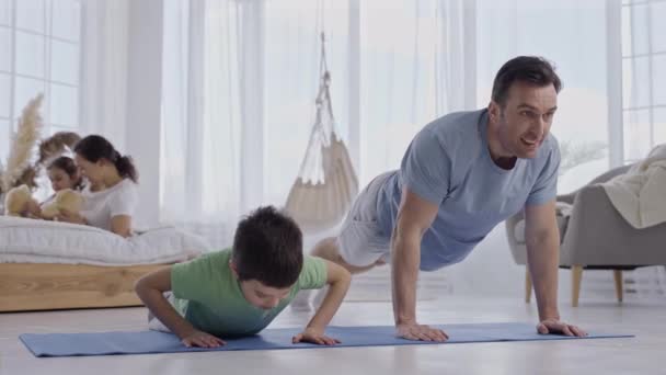 Alegre papá e hijo haciendo flexiones en casa — Vídeos de Stock