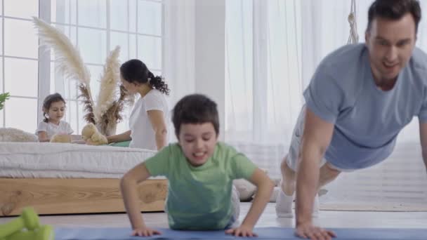照顾爸爸教儿子在地板上做俯卧撑 — 图库视频影像