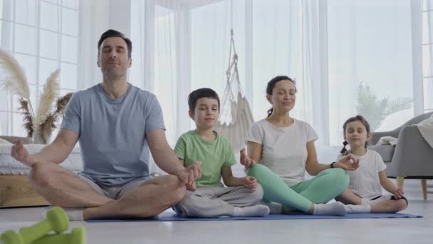 Atrakcyjna rodzina z dziećmi uprawiającymi jogę w pomieszczeniach — Wideo stockowe