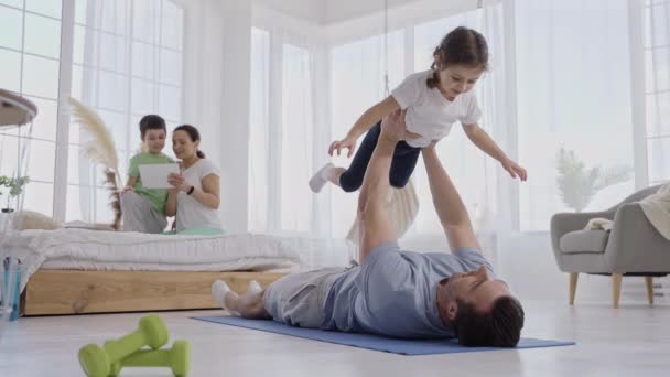 Sevgi dolu bir baba. Kollarını kaldırarak kızını eğitiyor. — Stok video