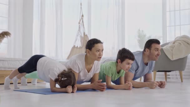 Спортивная семья, стоящая на доске во время занятий йогой — стоковое видео