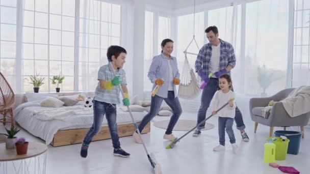 Feliz familia bailando diversión mientras limpia la casa — Vídeos de Stock