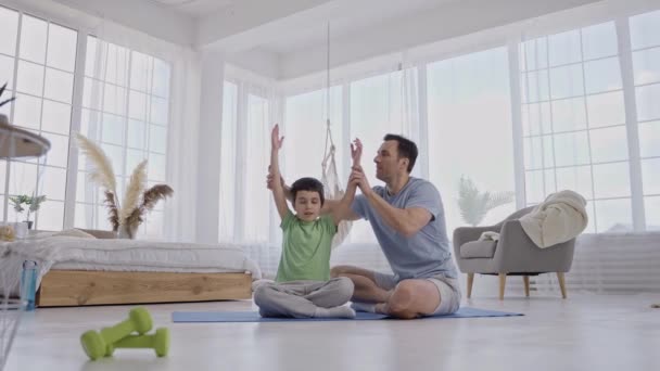 Cuidar do pai ajudando o filho a manter a postura de ioga dentro de casa — Vídeo de Stock