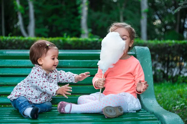 Маленькая девочка с сахарной ватой во время сидения — стоковое фото