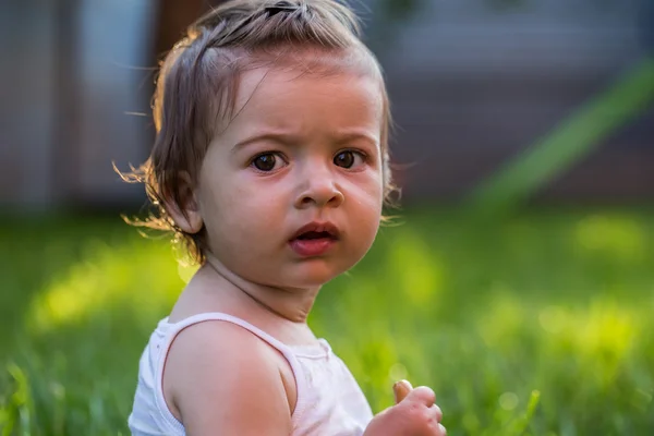 Эмоции маленькая девочка, на фоне зеленой травы — стоковое фото