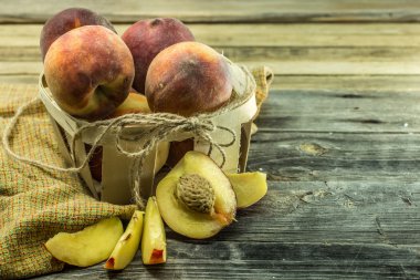 Metin için ahşap arka plan yeri üzerinde bir sepet dilimlenmiş ve bütün sulu şeftali, closeup