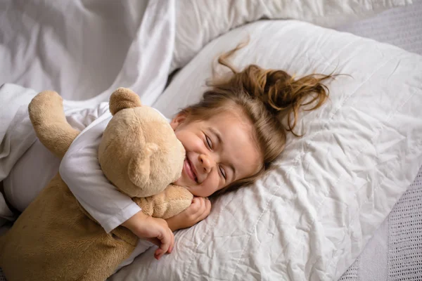 Μικρό κορίτσι στο κρεβάτι με μαλακό παιχνίδι τα συναισθήματα ενός παιδιού — Φωτογραφία Αρχείου