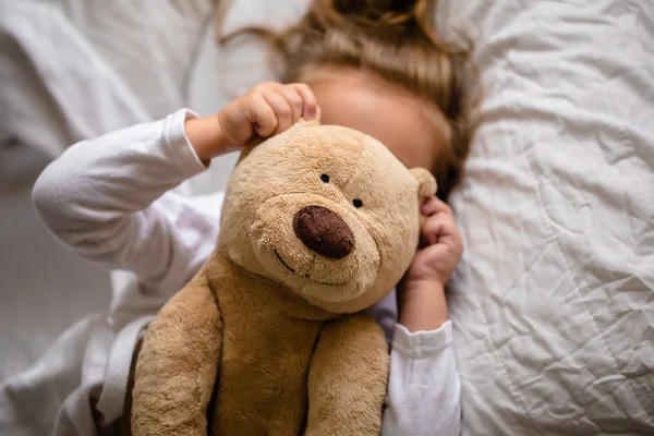 Μικρό κορίτσι στο κρεβάτι με μαλακό παιχνίδι τα συναισθήματα ενός παιδιού — Φωτογραφία Αρχείου