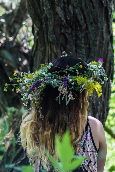 Schönes Mädchen in einem Blumenkranz am Ufer des Flusses, sonniger Tag. — Stockfoto