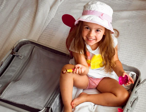 Bella bambina seduta in valigia con giocattoli zaino sulle spalle — Foto Stock