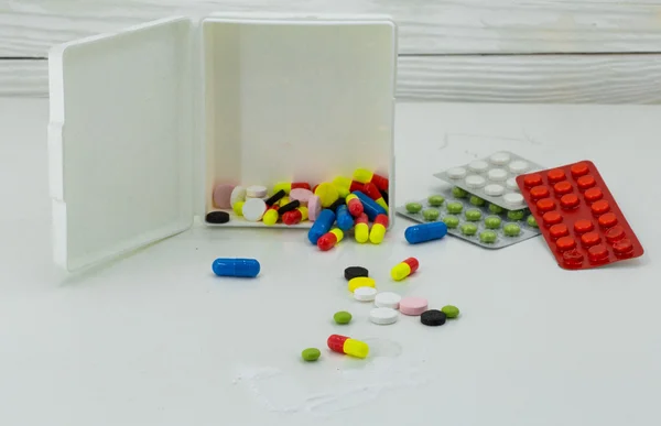 Léky, prášky různé barvy na bílém podkladě, drogy zdraví — Stock fotografie
