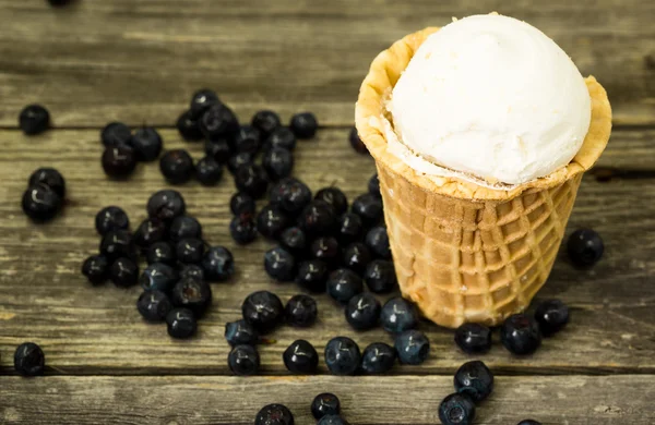 Мороженое в вафельной чашке с черникой на деревянном фоне — стоковое фото