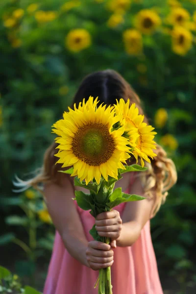Молодая красивая женщина стоит в поле подсолнухов, закрытое лицо — стоковое фото