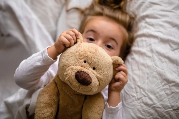 Niña en la cama con juguete suave las emociones de un niño — Foto de Stock