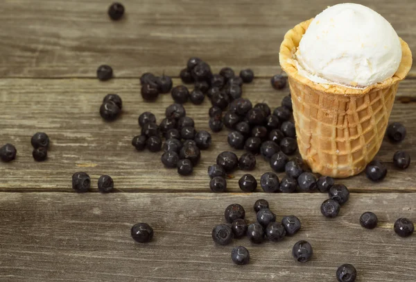 Мороженое в вафельной чашке с черникой на деревянном фоне — стоковое фото