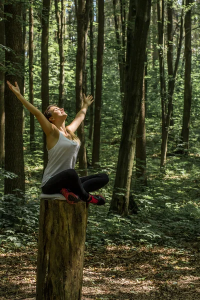Schöne sportliche Mädchen im Wald auf einem Baumstumpf in Yoga, Sport — Stockfoto