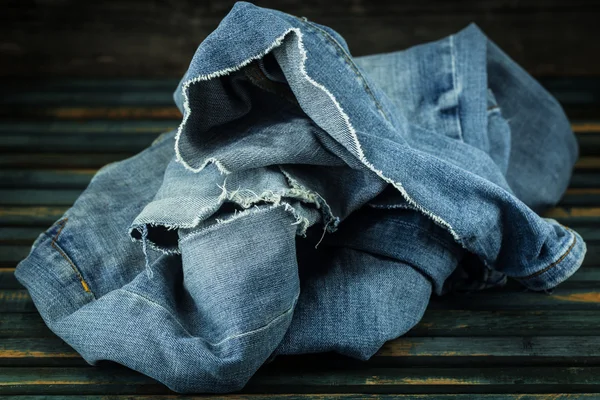 Banda džíny na dřevěné pozadí rozházené, módní oblečení — Stock fotografie