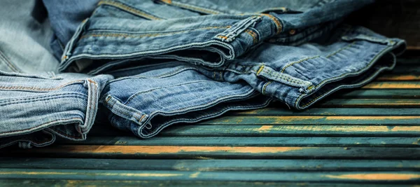 Banda džíny na dřevěné pozadí rozházené, módní oblečení — Stock fotografie
