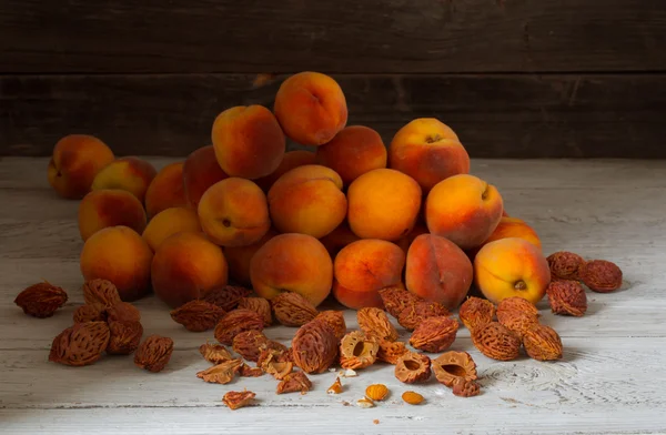 Beautiful fruit and lots of peach pits from peaches on wooden background — Stock Photo, Image