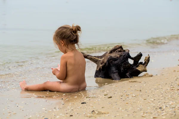 Niña desnuda juega en el mar, hermosa playa — Foto de Stock