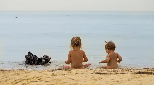 Dos niñas en el desnudo jugando en el mar — Foto de Stock