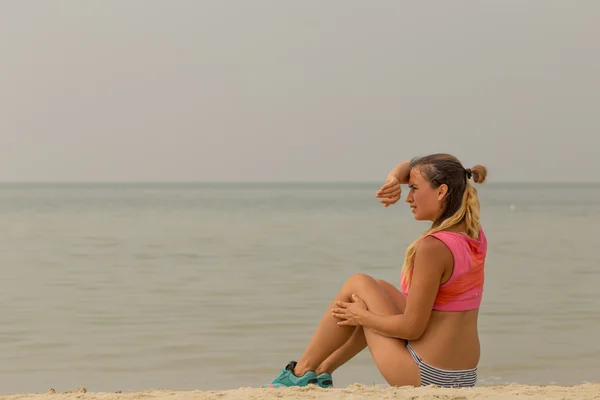 beautiful sporty girl on the beach resting after sport