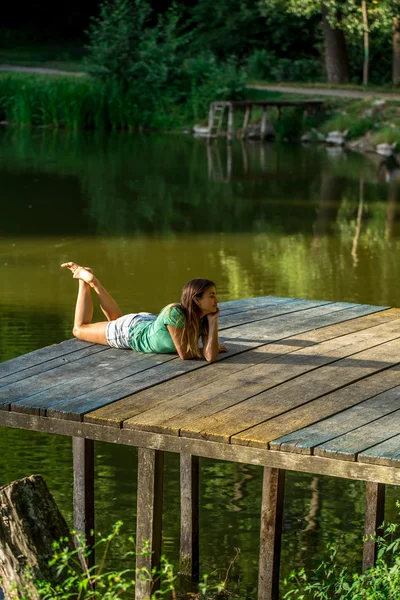 Schönes Mädchen auf Holzsteg liegend — Stockfoto