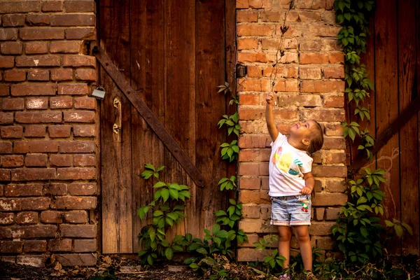 Linda menina brincando perto de edifícios abandonados e portas antigas — Fotografia de Stock