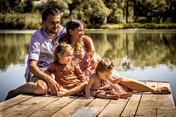 Familia joven en el muelle cerca del lago — Foto de Stock